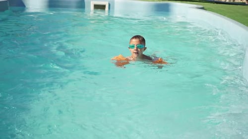 Child Swims in the Pool on a Sunny Summer Day