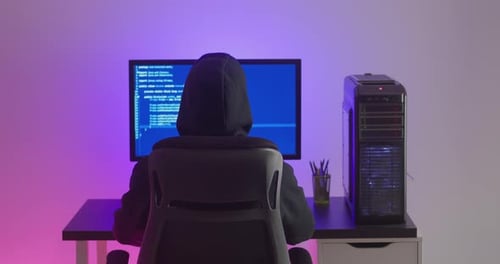 Rückansicht von Man Hacker in Hood, der am Computer arbeitet