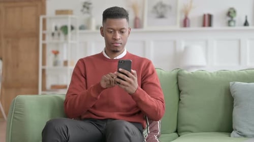 Young Adult Using Mobile Phone on Couch at Home