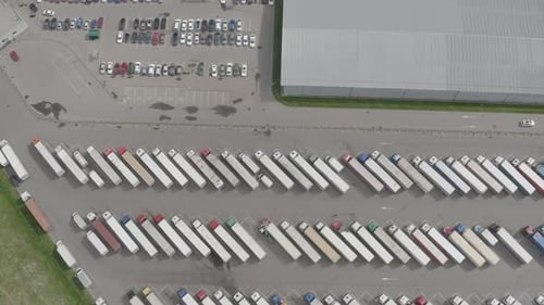 Logistic warehouse parking lot with many semi trucks with cargo trailers waiting