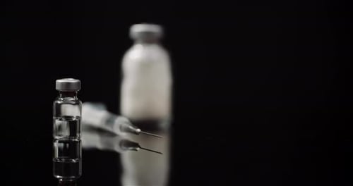 Medical Syringe and Bottles on a Black Surface