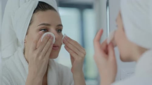 Woman Removing Makeup in Bathroom with Cotton Pads