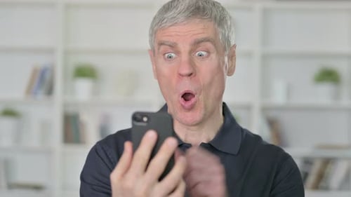 Man Cheers While Using Smartphone Indoors