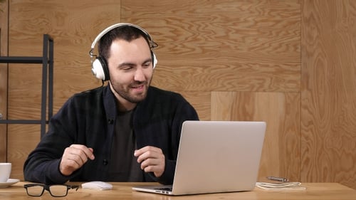 Young adult listening to music while working on laptop