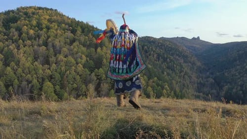 Dança energética de um velho xamã com um pandeiro no fundo da paisagem de montanha de outono
