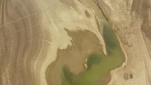 A dry lake bed showing little remaining water and lines where water has disappeared, during a drough