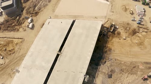 Aerial footage of a large scale highway construction site with trucks, excavators and loaders workin