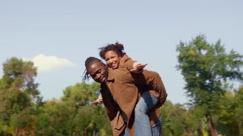 Joyful Dad Piggyback Kid in Sunny Park
