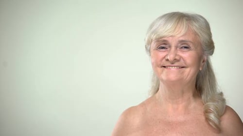 Senior Woman Smiles and Touches Her Face