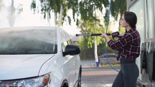 Woman Washes Car at Urban Carwash on Sunny Day