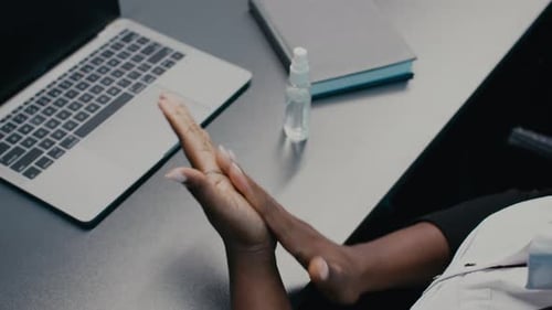 Woman Applies Hand Sanitizer at Work Desk