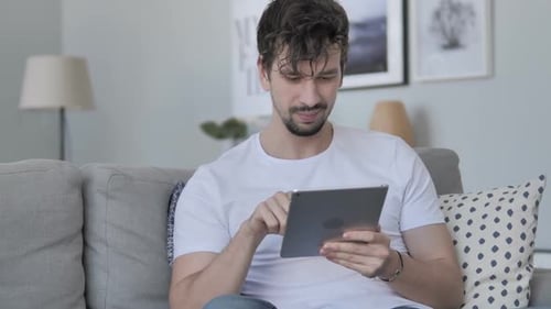 Young Adult Using Tablet on Couch at Home