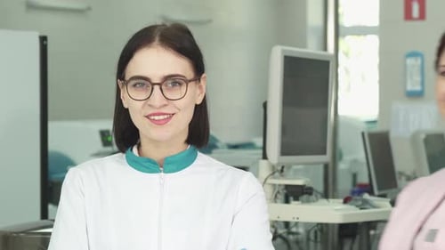Two Young Women in Lab Coats Smiling at Camera