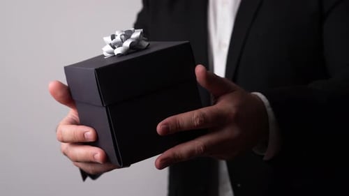 Man in Suit Holds Black Gift Box