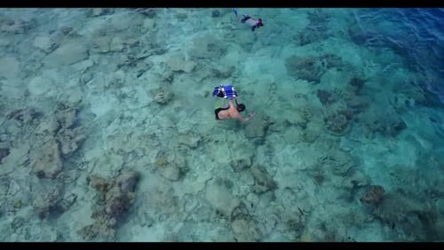 Man and lady sunbathing on idyllic seashore beach holiday by shallow sea with white sand background
