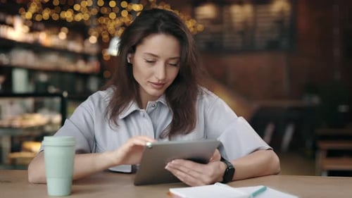 Positive Woman Using Digital Tablet While Sitting at Cafe