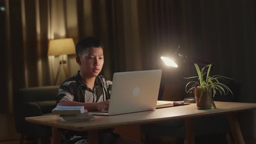 Student Works on Laptop at Desk in Evening