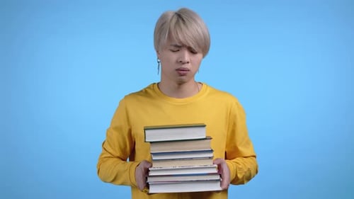 Asian Bored Man As Student is Dissatisfied with Amount of Homework and Books