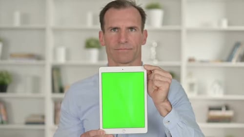 Man Holds up Tablet with Green Screen