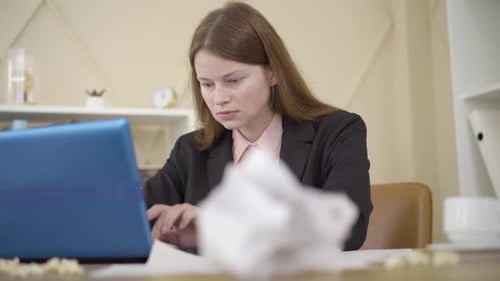Mujer caucásica diligente escribiendo en una computadora portátil y comprobando la hora