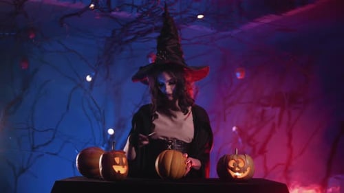 Woman in Witch Costume Carving Pumpkin