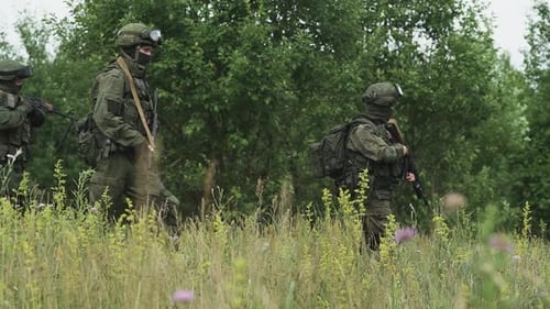 Soldaten in Tarnung mit Sturmgewehr gehen durch das Feld Militärische Aktion in der Steppe