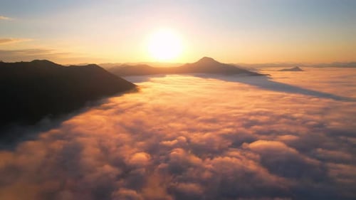4K Scenic flight over beautiful mountain scape with bright sky and clouds