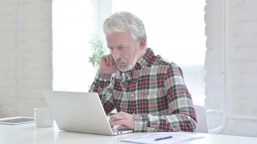 Senior Man Using Laptop at Desk