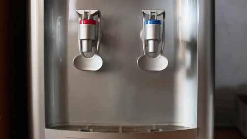 Mano humana vertiendo agua fría en vidrio desde un dispensador de agua