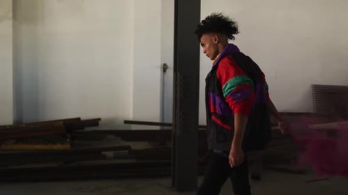 Mixed race man holding purple flare walking through an empty building