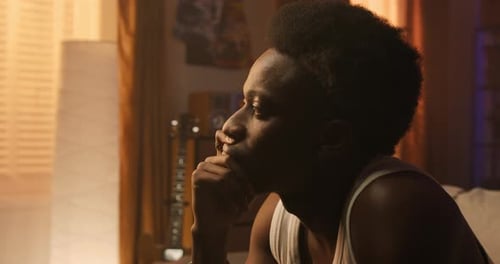 Lonely Guy Sits in Living Room on Couch Man Stares at Window Thoughtful Sad Longing Hurt
