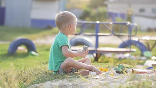 Child Plays with Toys in a Sandbox