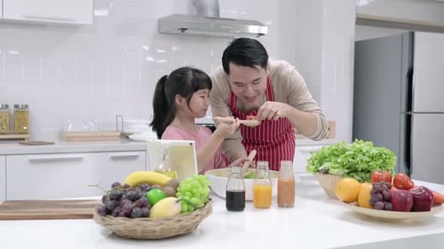 Child and Parent Cooking Salad in Modern Kitchen