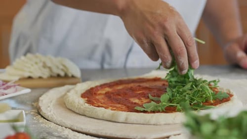 Person Adding Greens to Pizza Dough