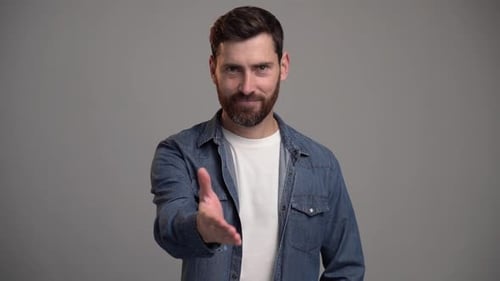 Portrait of bearded man standing with outstretched hand, offering handshake to partner, greeting