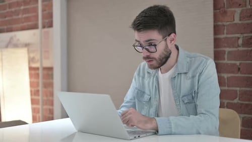 Excited Man Celebrating Success Using Laptop at Desk