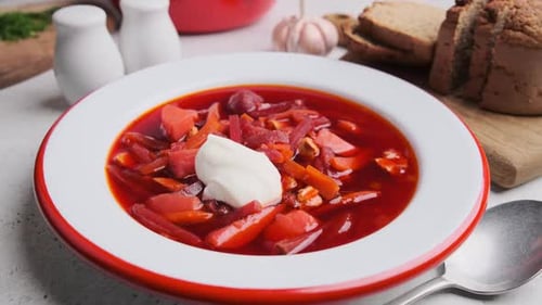Rote-Bete-Suppenborsch mit Sauerrahm, Dill und Brot mit einem Löffel essen.