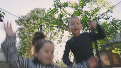 Happy Children Jumping on Trampoline in Backyard