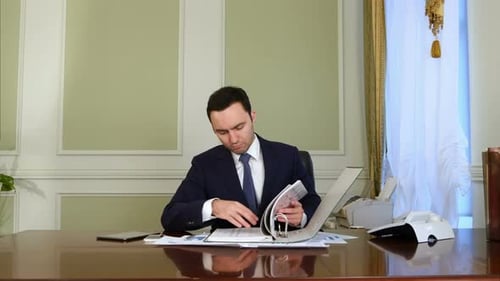 Man in Suit Examines Documents in Office