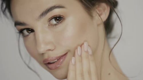 Close-up of Pretty Woman Moisturizing Face with Her Arm and Looking To Camera