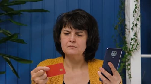 Woman Holds Credit Card and Smartphone Indoors
