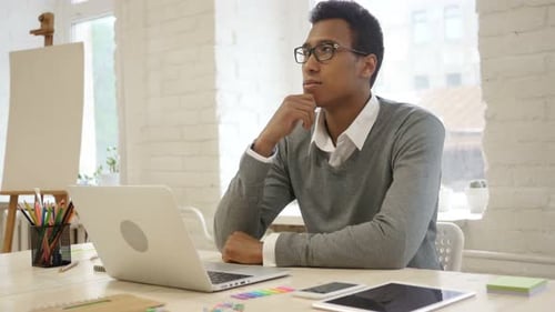 Young Adult Contemplating Technology in Modern Office