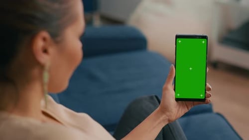 Woman Holding Phone with Green Screen at Home