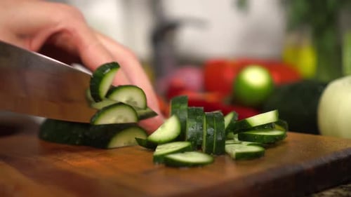 Slicing Cucumber with Knife on Cutting Board
