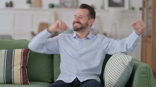 Happy Man Dancing and Enjoying While Sitting on Sofa