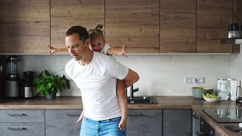 Dad Gives Daughter Piggyback Ride in Kitchen
