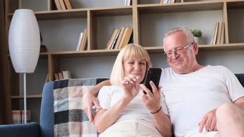 Mature Couple Relaxing at Home with Mobile Phone