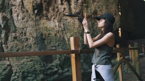 Chica turista tomando fotos de la cueva de Devetashka en Bulgaria durante un viaje de vacaciones