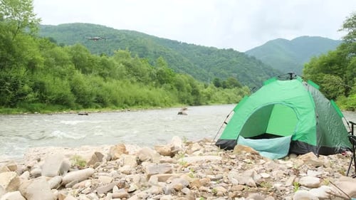 A Drone Flies Over a Tent Near a Mountain River