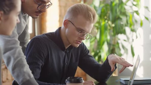 Young Adults Collaborating Around Laptop in Bright Office